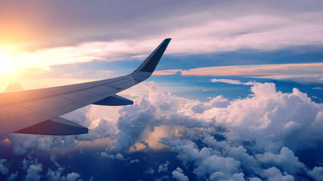 View of an airplane wing over clouds during sunset or sunrise