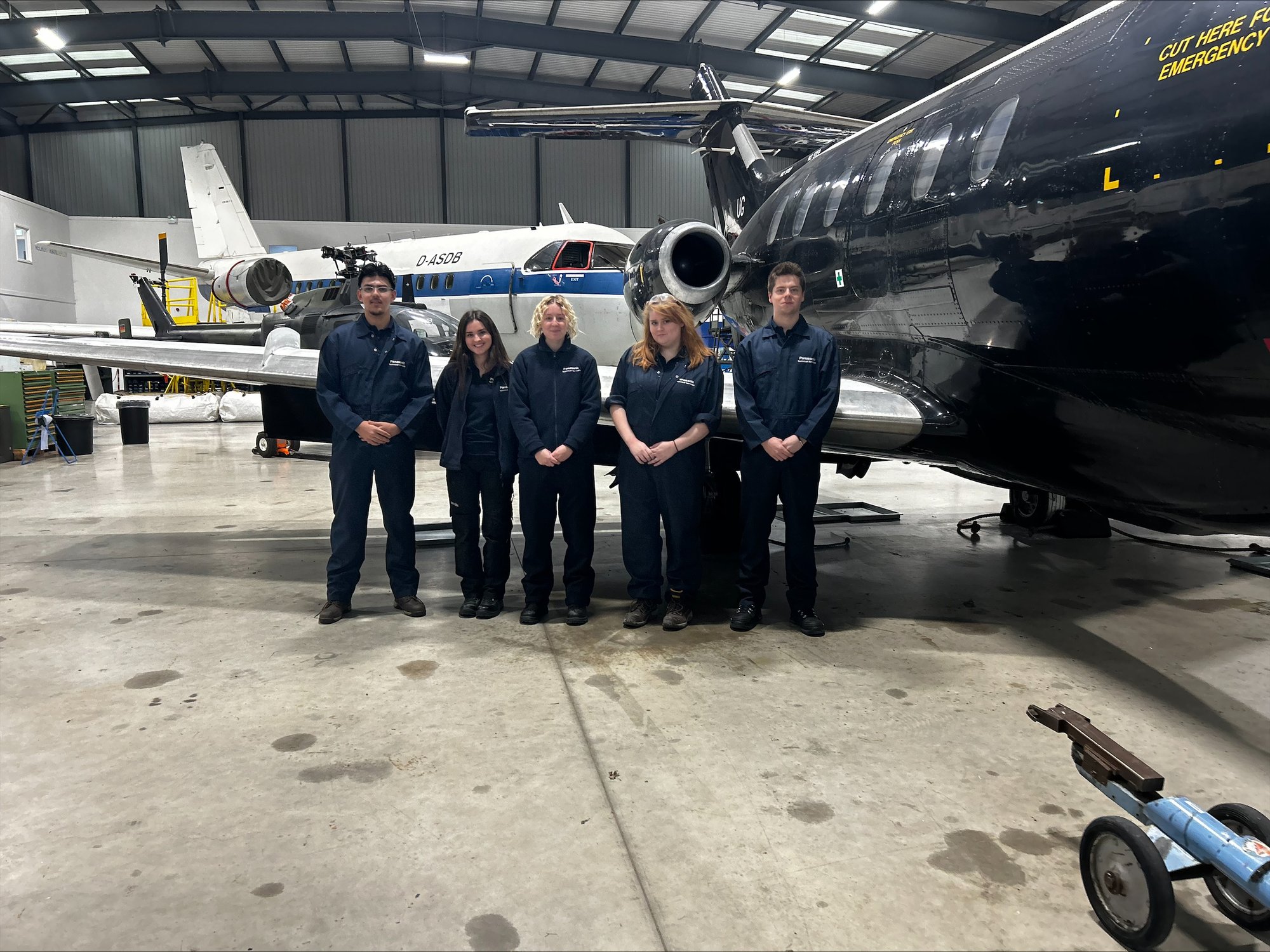 Five people standing in front of an airplane hangar