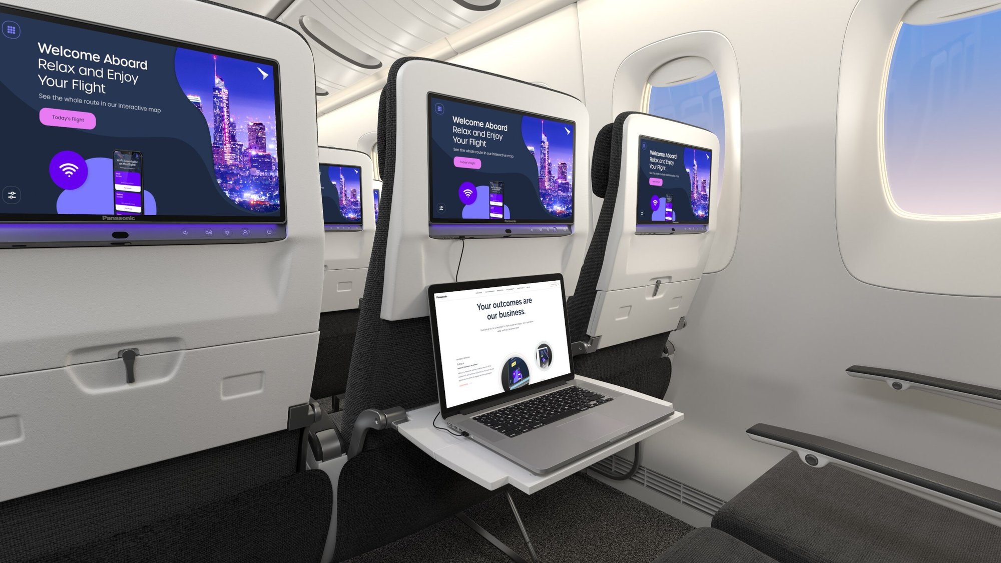 Airplane cabin with personal entertainment screens and a laptop on a tray table